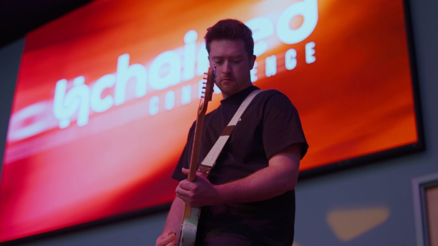 Musician performing at a conference with dramatic stage lighting — professional event video production